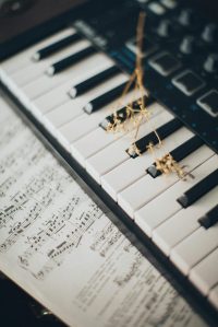 Close-up of piano keys with a flower and sheet music creates an artistic and musical ambiance.