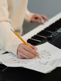 Creating music sheets while playing piano. Perfect for education and creativity themes.